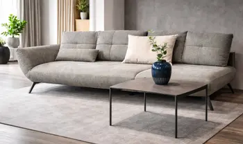 Modernes Wohnzimmer mit großem grauem Sofa, dekorativen Kissen, schlichtem Couchtisch und stilvoller Vase in heller, wohnlicher Atmosphäre.